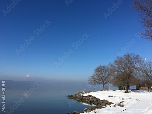 Winter scene, park, river, snow, blue sky, bare trees
