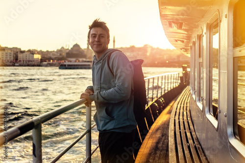 Photography A young smiley man on a ferry floats to the shores of Istanbul, Turkey in the rays of sunset