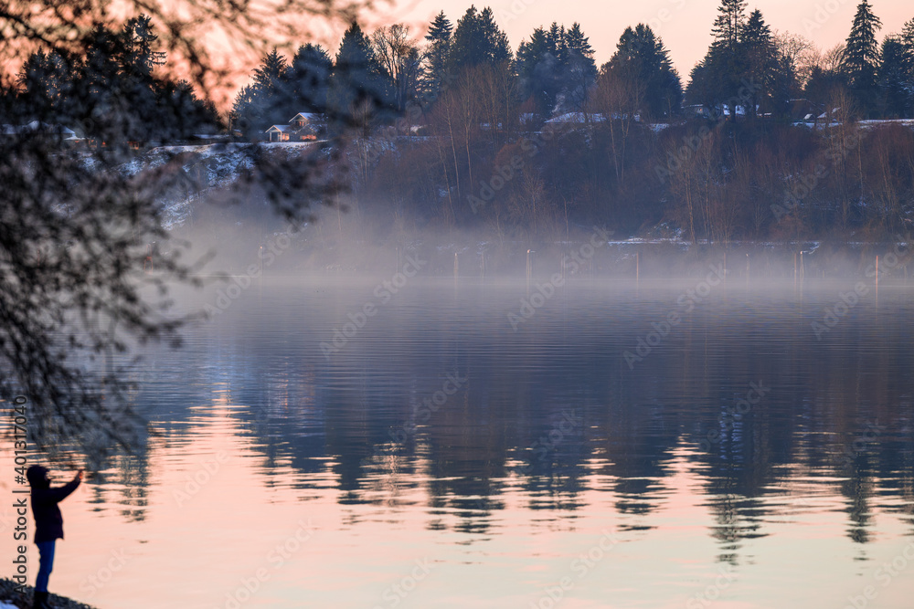 Person taking photo along river during December sunset