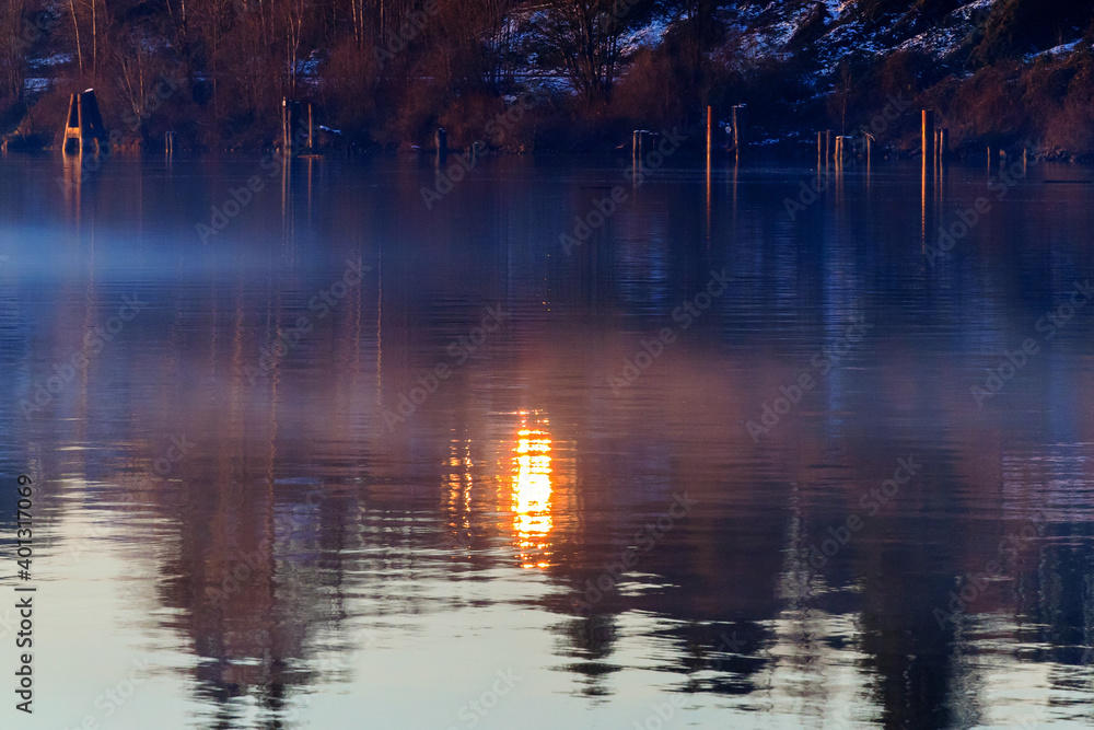 Sunlight reflecting in river, fog hovers above