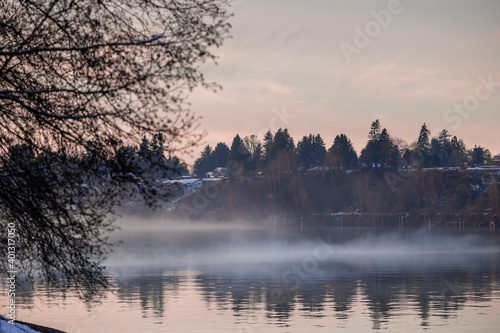 Obraz na płótnie Fog sweeps over river during December sunset after snowfall w salonie