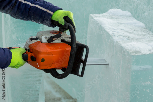Close-up of a fitter's hands with a chainsaw cutting an ice block
