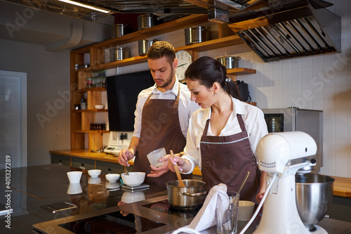 Man and woman cooking together in the kitchen of bakery. Profession preparation confectionery products
