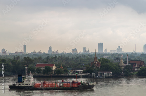 Bangkok, thailand - Oct 03, 2020 : Gas LPG tanker sailing in Chao Phraya river and through the front of Bang Krachao Nok Temple Pier. Focus and blur.