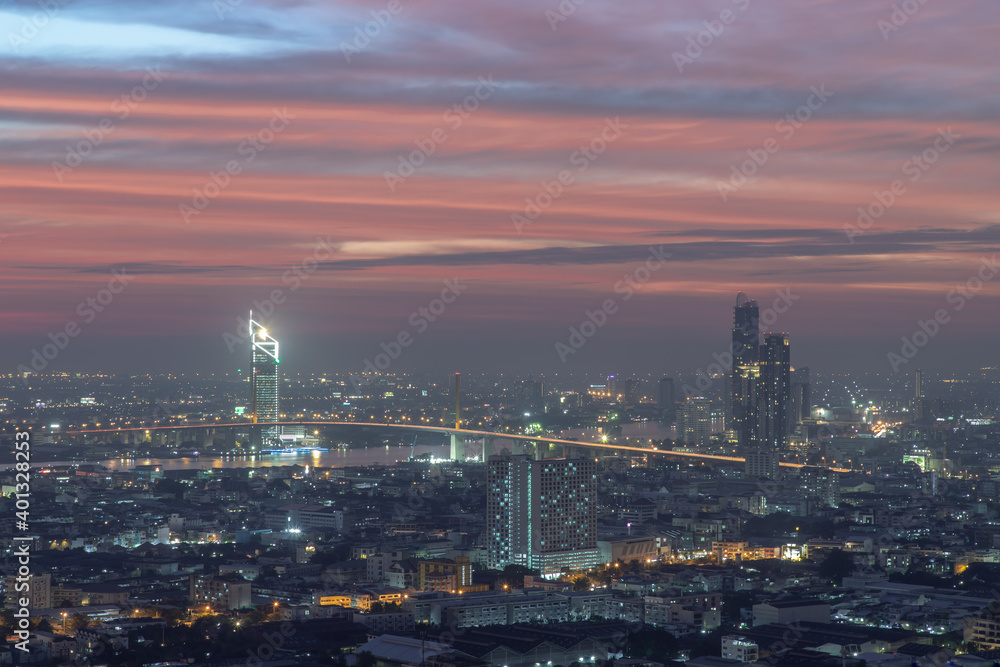 Bangkok, thailand - Dec 23, 2020 : Aerial view of Bangkok city Overlooking Skyscrapers and the Bridge crosses the Chao Phraya river with bright glowing lights at dusk. No focus, specifically.