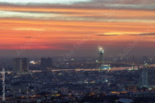 Bangkok, thailand - Dec 23, 2020 : Aerial view of Bangkok city Overlooking Skyscrapers and the Bridge crosses the Chao Phraya river with bright glowing lights at dusk. No focus, specifically. © num