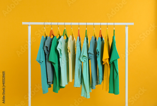 Rack with stylish children clothes on yellow background © New Africa