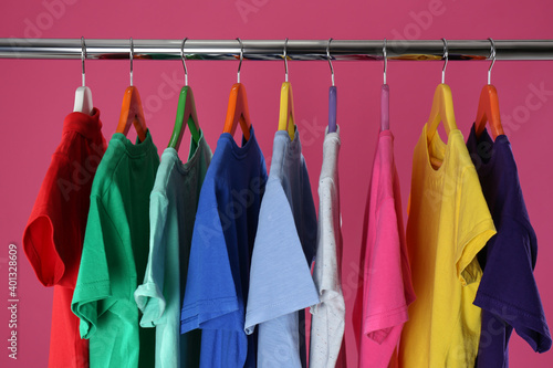Rack with stylish children clothes on pink background, closeup