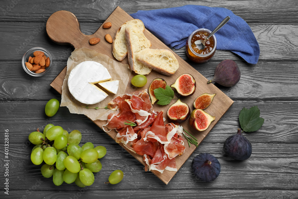 Board with delicious figs, proscuitto, cheese and grapes on grey wooden table, flat lay Board with delicious figs, proscuitto, cheese and grapes on grey wooden table, flat lay