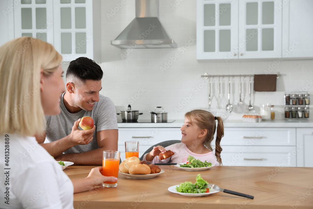 Happy family having breakfast together at table in modern kitchen Happy family having breakfast together at table in modern kitchen