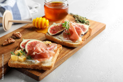 Delicious sandwiches with figs, proscuitto and cheese on light table, closeup