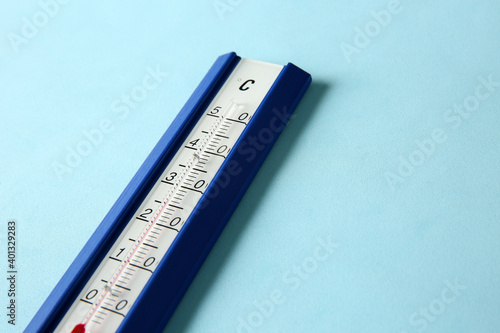 Weather thermometer on light blue background, closeup. Space for text