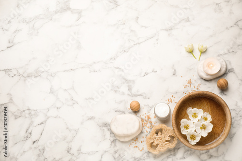 Flat lay spa composition with cream on white marble table, space for text