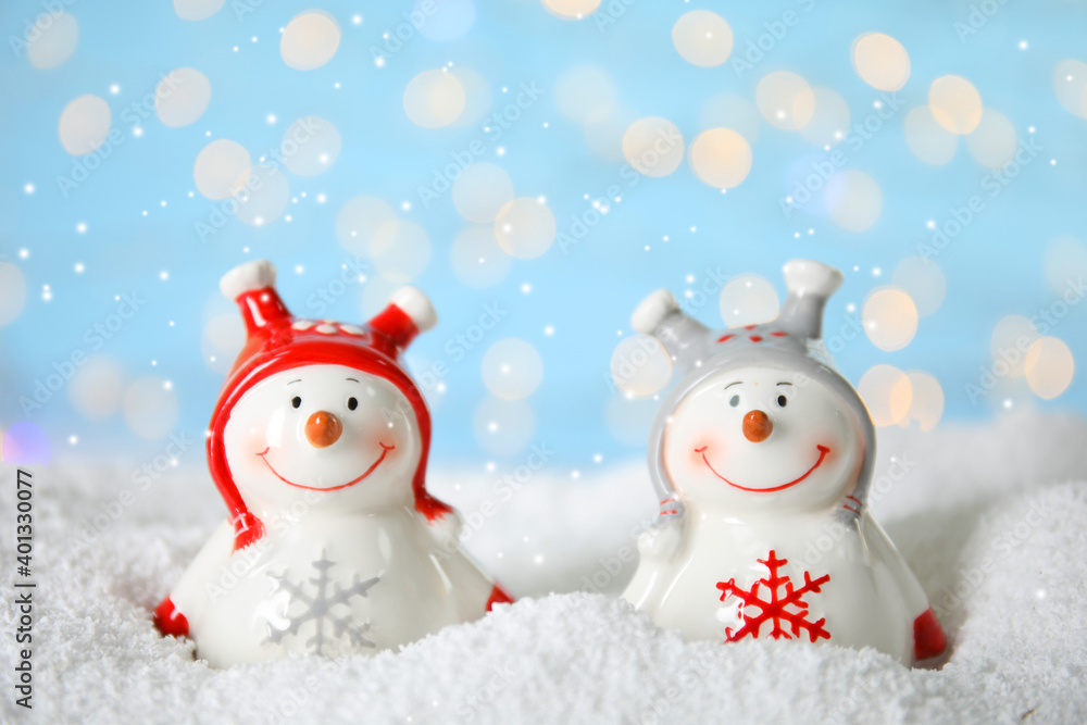 Decorative snowmen on artificial snow against blurred festive lights Decorative snowmen on artificial snow against blurred festive lights