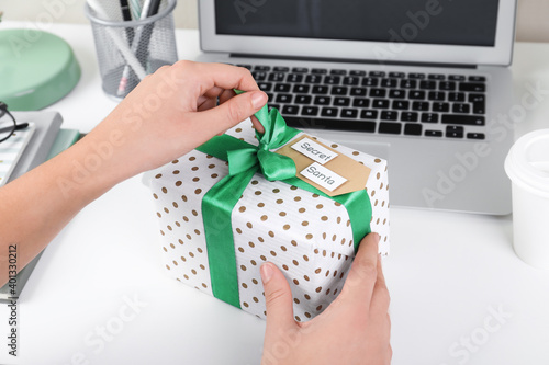 Woman opening present from secret Santa at workplace, closeup
