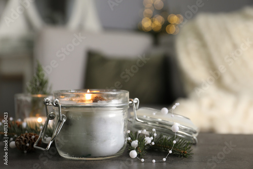 Fotografia Burning scented conifer candle and Christmas decor on grey table indoors