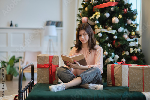 Photo of pretty young lady cuddle paper book. christmas holidays and people concept happy young woman with pencil and notebook writing in bed at home bedroom © yavdat