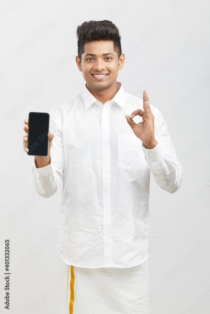 Cheerful Young Indian man showing smart phone in traditional dress against white. Cheerful Young Indian man showing smart phone in traditional dress against white.