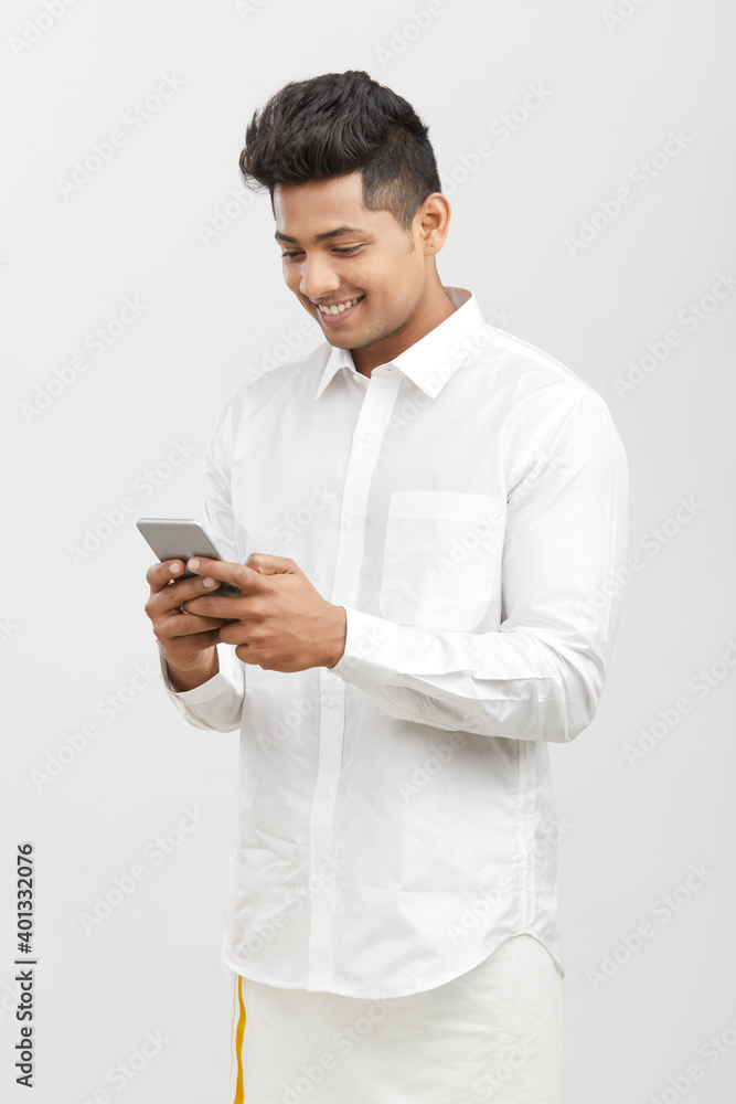 Traditional south Indian young man using smartphone on white Traditional south Indian young man using smartphone on white
