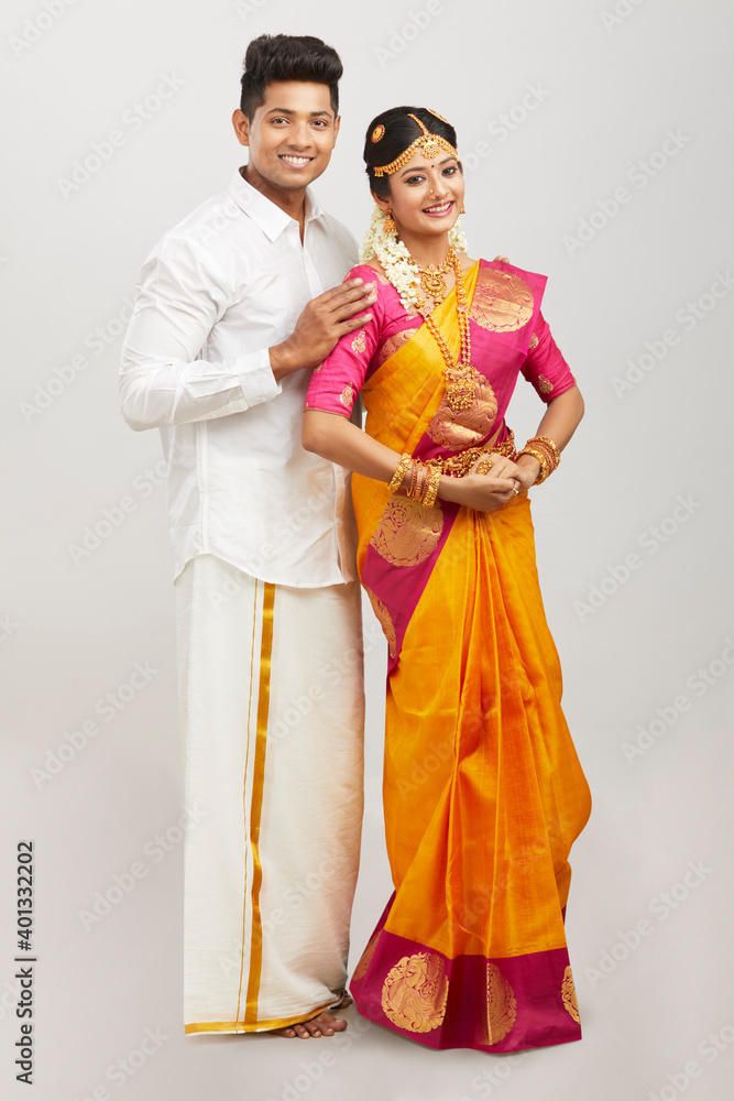 Attractive happy south Indian couple in traditional dress on white.