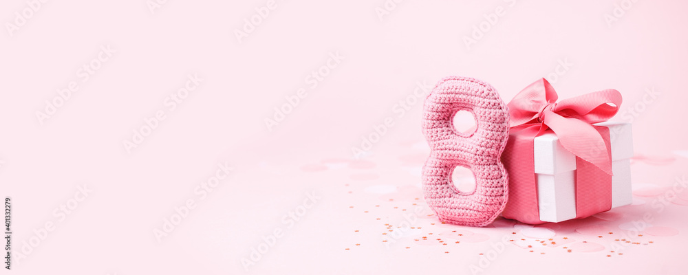 8 March, International Women's Day or Birthday concept. Figure eight of pink crochet with luxury gift box, big bow on pink background. Space for text, monochrome seasonal holiday greeting card