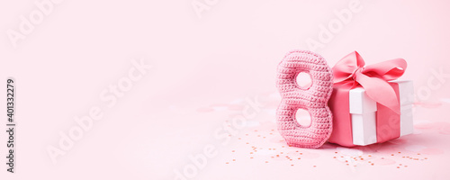 8 March, International Women's Day or Birthday concept. Figure eight of pink crochet with luxury gift box, big bow on pink background. Space for text, monochrome seasonal holiday greeting card © misskaterina