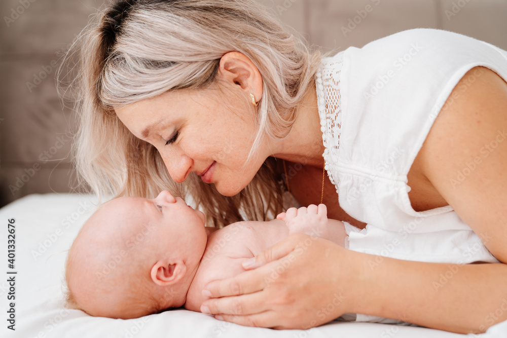 mom is mom is lying down with a baby in a white bed after feeding breast milk. mom is mom is lying down with a baby in a white bed after feeding breast milk.