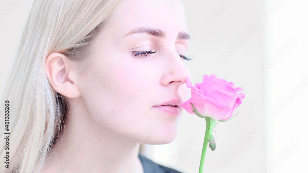 Beautiful young woman with delicate rose flower. Girl clean fresh skin touching her face in flowers. soft focus, selective focus
