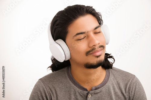 Young man listening music in headphones on white background.
