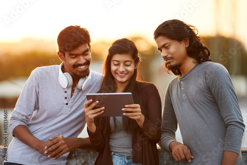 Cheerful young friends playing in digital tablet on terrace at outdoor. photo