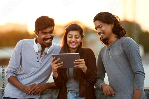 Photography Cheerful young friends playing in digital tablet on terrace at outdoor