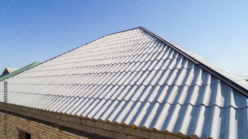 Modern roof. Roof covering. Roman profile. The roof of the house is covered with wavy gray tiles. Modern roof. Roof covering. Roman profile. The roof of the house is covered with wavy gray tiles.