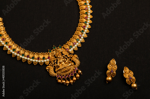 Traditional Indian Gold Necklace With Earrings on black background.