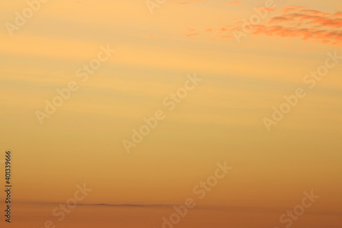 Sun below the horizon and clouds in the fiery dramatic orange sky at sunset or dawn backlit by the sun. Place for text and design