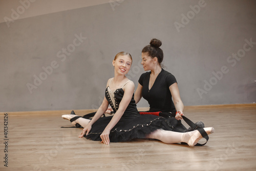 Cute little ballerina in black ballet costume. Young lady is dancing in the room. Girl in dance class with teatcher.