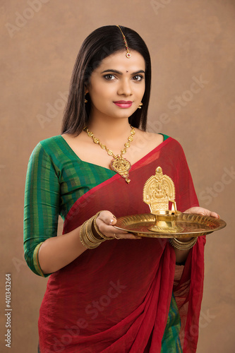 Hindu Indian young women holding Deepam in hands studio shot. ( Kamatchi vilakku ) photo