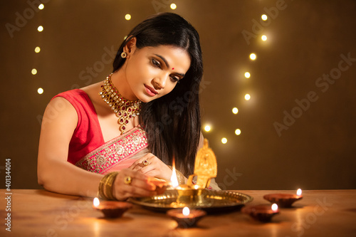 Beautiful Hindu Indian young women lightening Diya on Diwali day.
