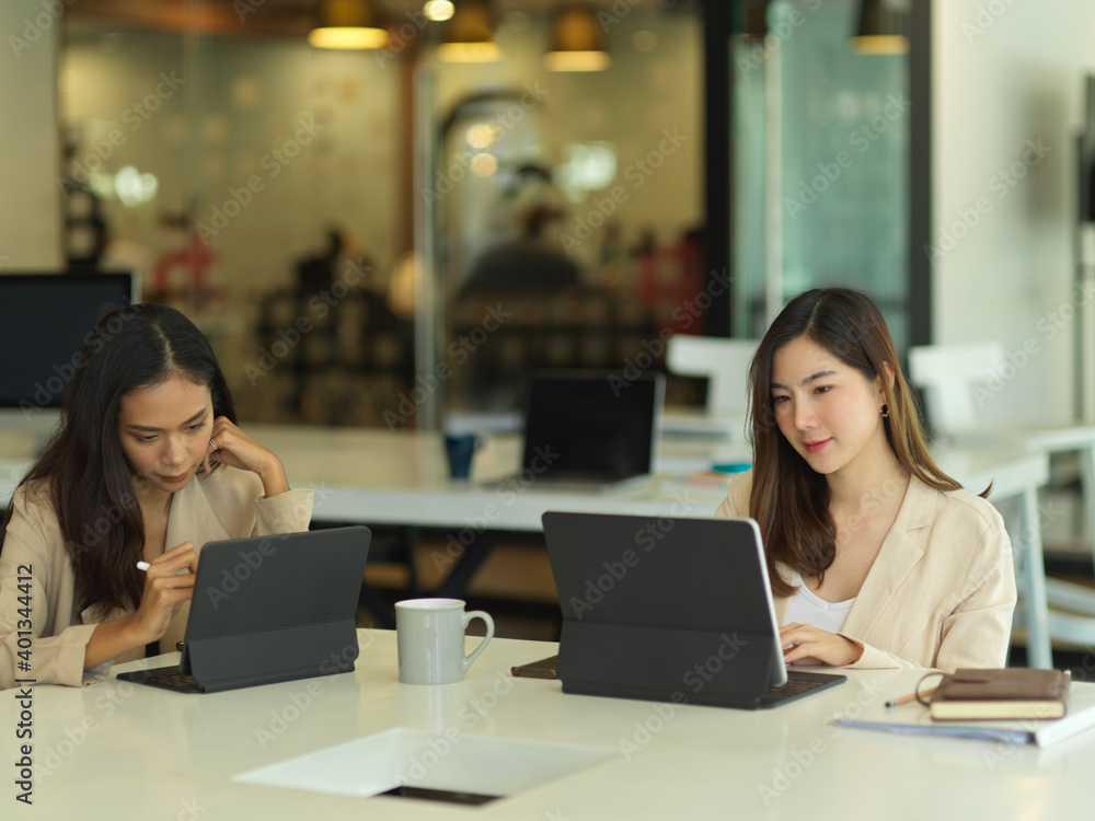 Two female office worker working with digital tablets in meeting room Two female office worker working with digital tablets in meeting room