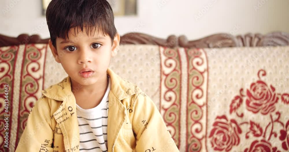 Slow-motion portrait of boy in dress seated at home during quarantined looks around lost lonely bored isolated because of new normal coronavirus pandemic social and physical distancing Slow-motion portrait of boy in dress seated at home during quarantined looks around lost lonely bored isolated because of new normal coronavirus pandemic social and physical distancing