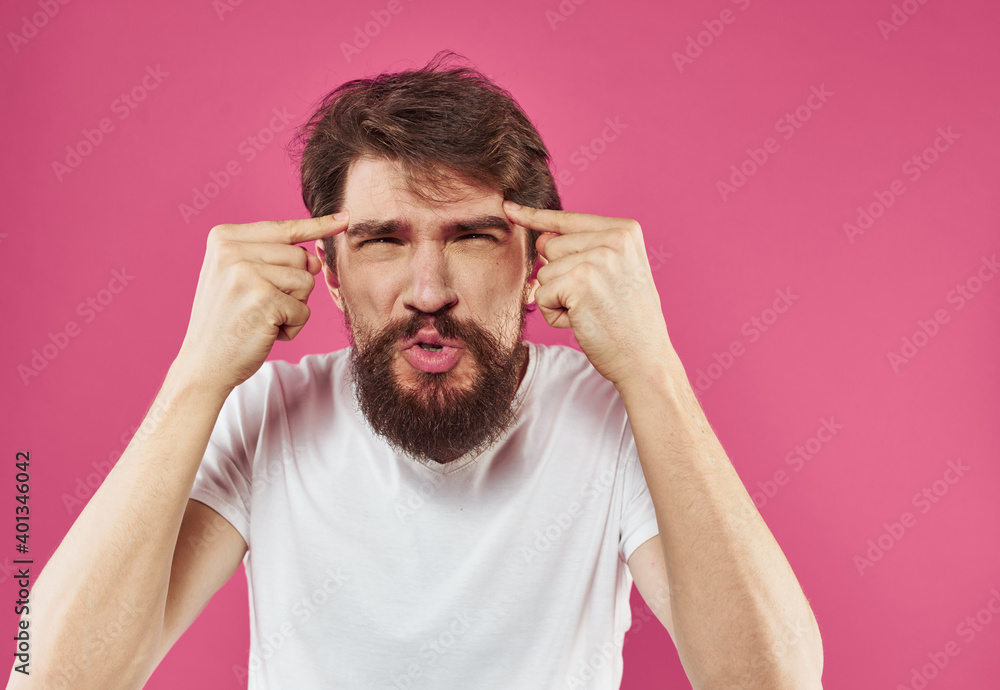 Man holds his hands near his face on a pink background stress irritability anger Man holds his hands near his face on a pink background stress irritability anger
