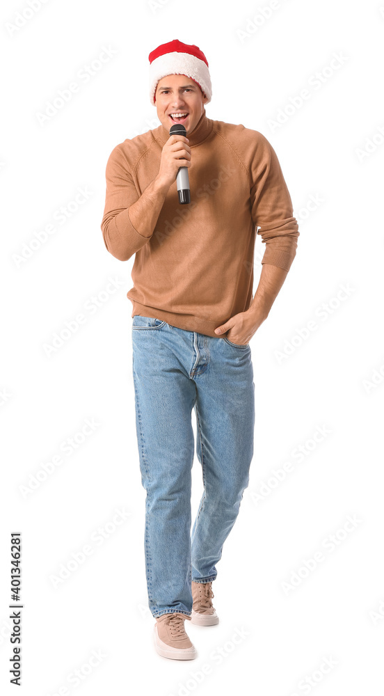 Young man with microphone singing Christmas song on white background