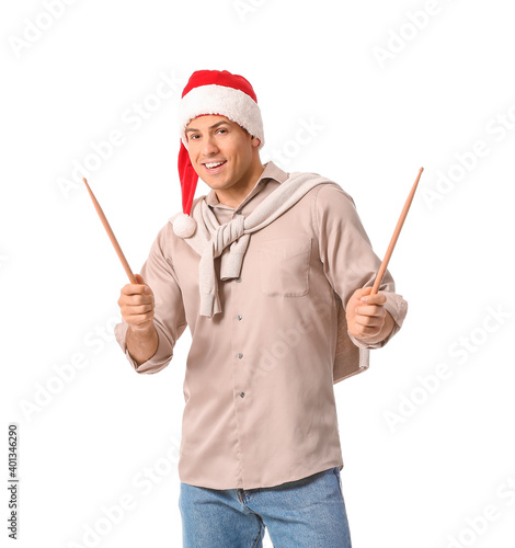 Young man in Santa hat and with drumsticks on white background