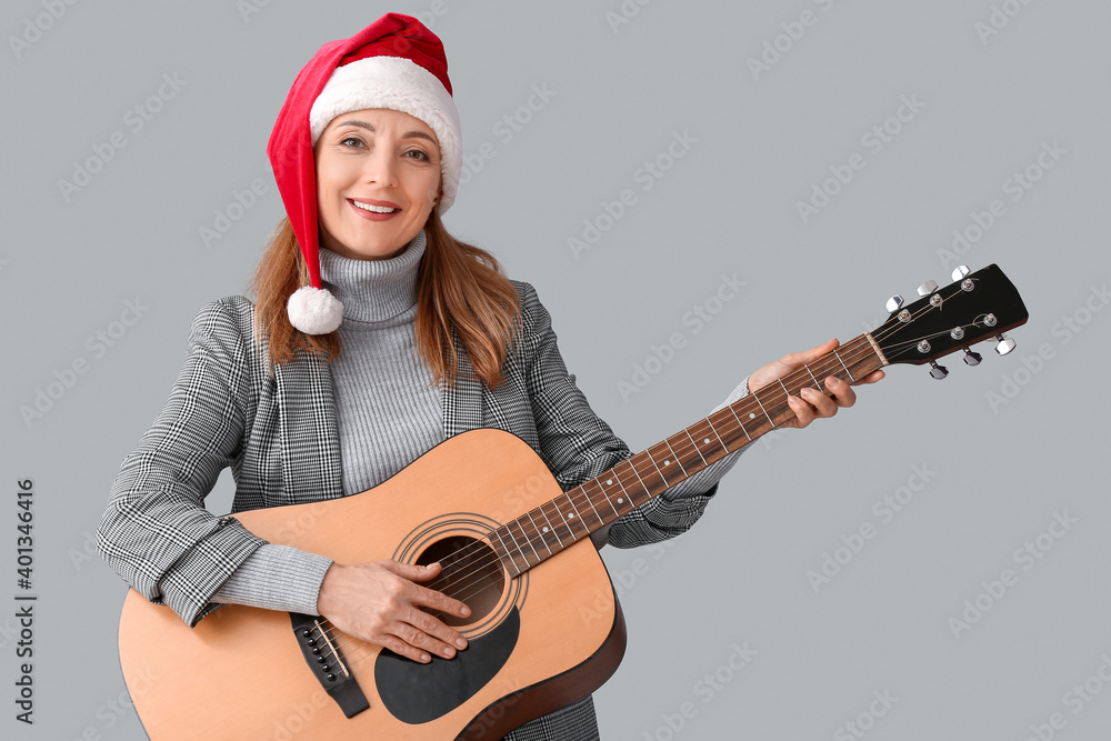 Fototapeta premium Mature woman playing guitar on grey background