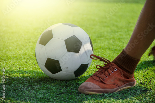 Students are kicking a black and white soccer ball.