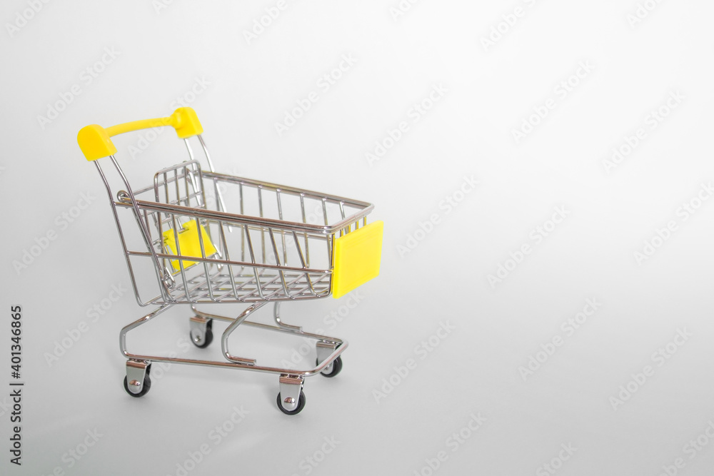 Grocery cart with yellow handle on a gray background. Side view. Horizontal format. Copyspace