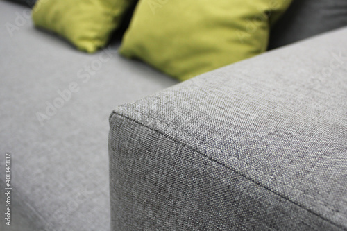 High-quality furniture seams. Seam on the armrest of the sofa. Modern upholstery fabric. A fragment of a gray sofa with green pillows. Close-up photos, selective focus.