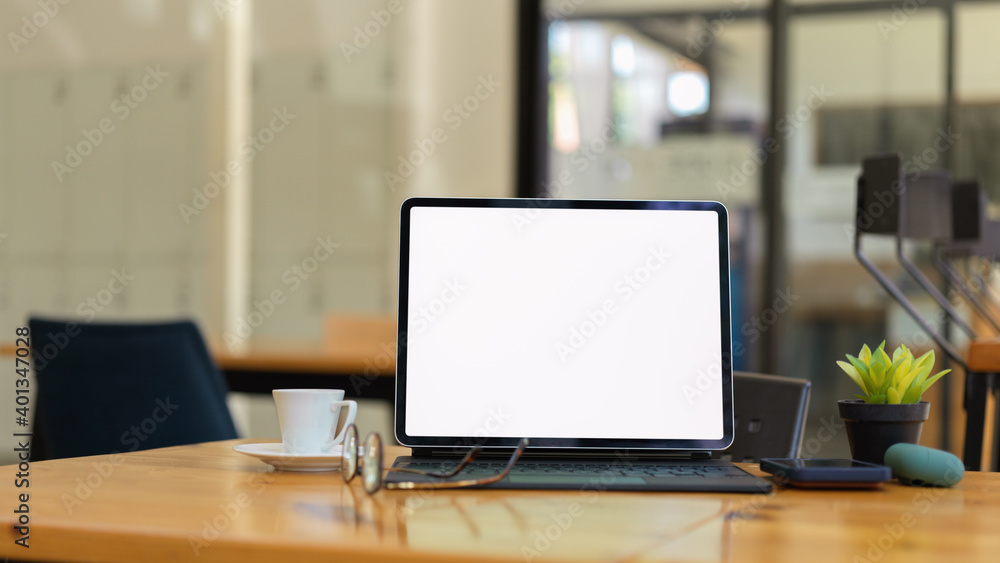 Glass partition office room with digital tablet and supplies on wooden table Glass partition office room with digital tablet and supplies on wooden table