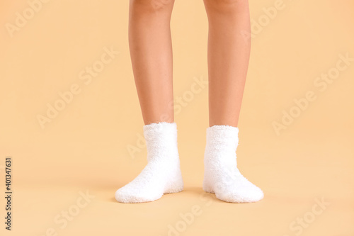 Legs of young woman in socks on color background