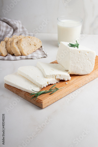 Adyghe cheese is cut into pieces on a wooden cutting Board on a light background. Soft goat cheese