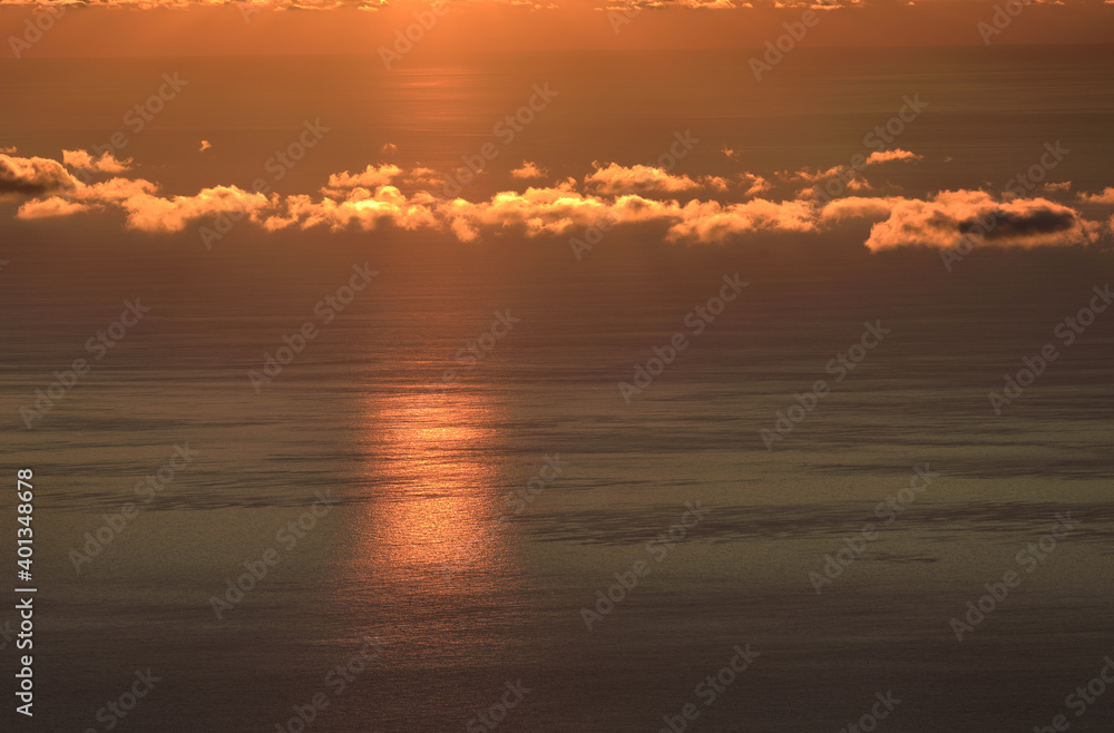 Obraz premium Clouds in the Golden light of the rising sun on the background of the sea surface